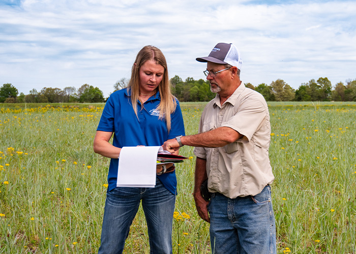 Two people reviewing documents in a field