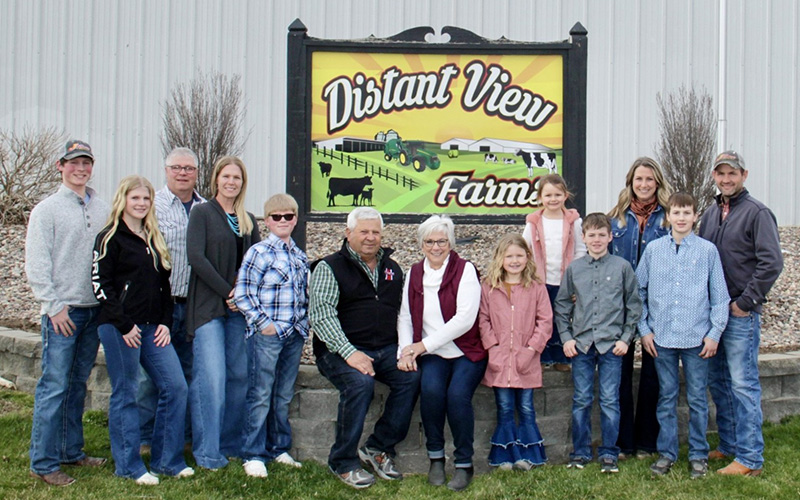 Thirteen people posing in front of a sign
