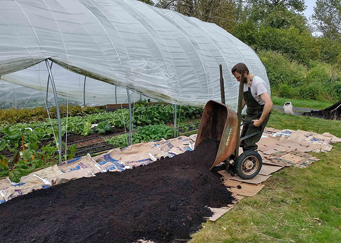 Person using a wheel barrel to dump soil