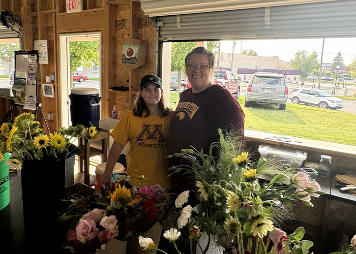Two people standing behind various flowers