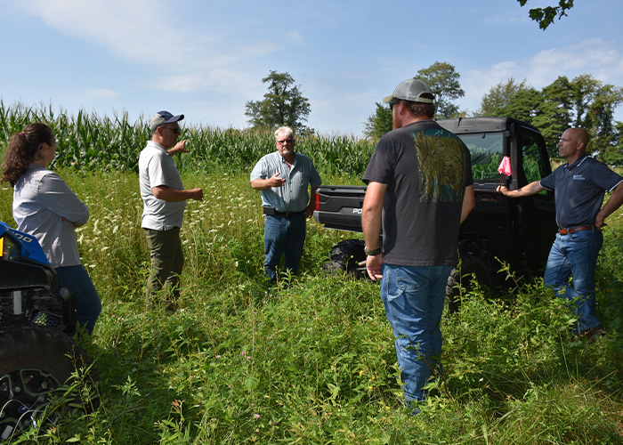 Five people standing next to a truck in a field