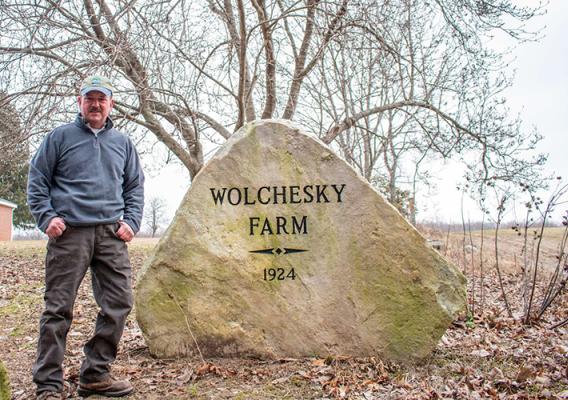 John Wolchesky, Jr. standing in front of his family rock for Wolchesky Farm.