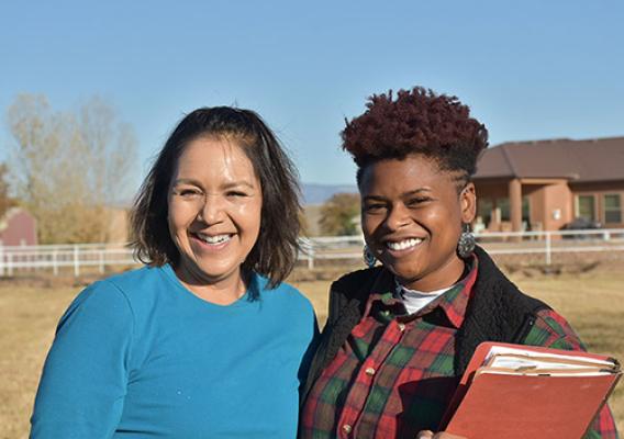 Two females standing together smiling.