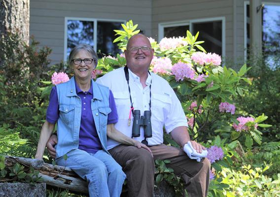 Mark and Beth Biser sit on a log bench, owners of Still Waters Farm in Mason County, Washington, sit on a bench in front of their farm.