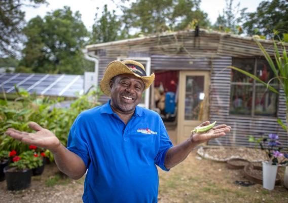 Bobby Wilson stands with arms open in aisle of his farm