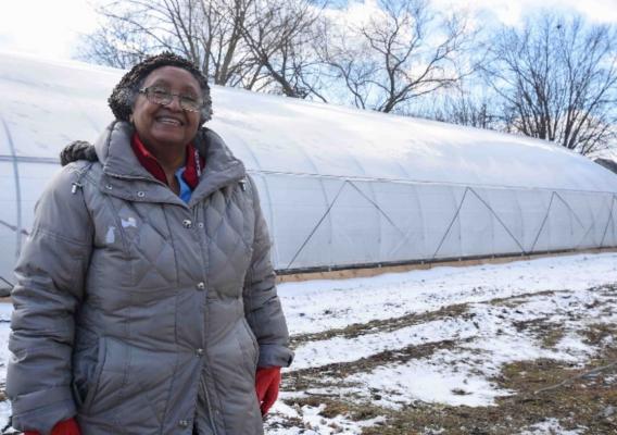 Person standing in front of greenhouse
