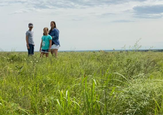 Three people standing in grassland