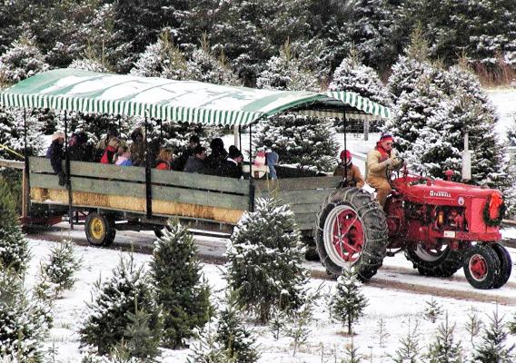 Red, snow covered tractor pulling a passenger trailer.