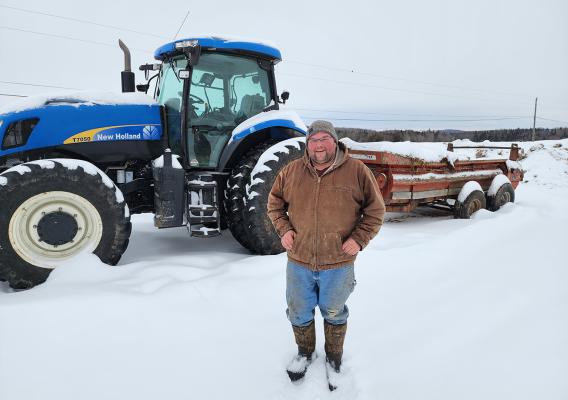 Person standing in snow in front of green tractor