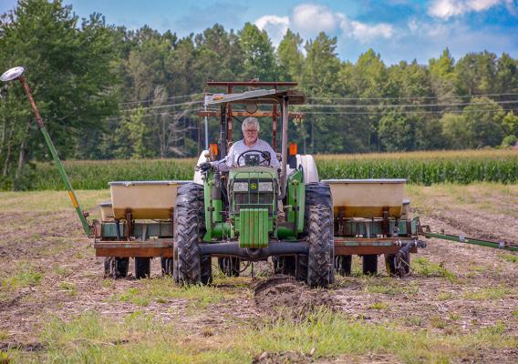 Person sitting in tractor while plowing