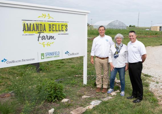 Three people standing in front of a sign