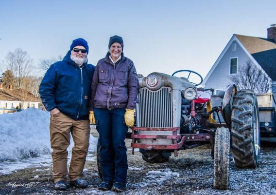 Two people standing in front of a vintage tractor