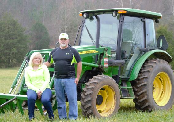 Two people sitting on a green tractor