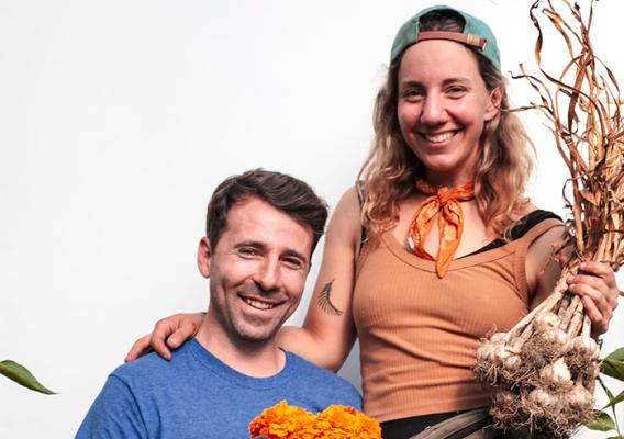 Two people holding fresh picked garlic and flowers