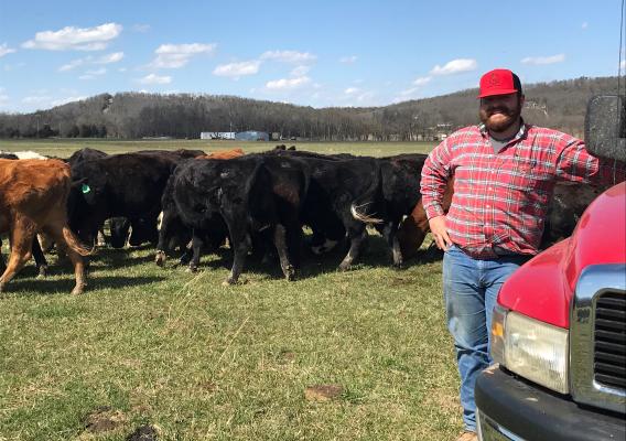 Beginning farmer McKenzie Fanning enjoys the mountain view with his cattle grazing in the background