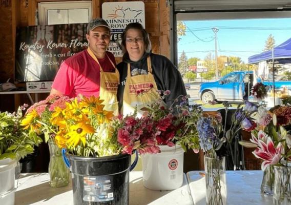 Two people standing behind a table of flowers