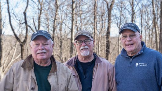 Three people standing in forest