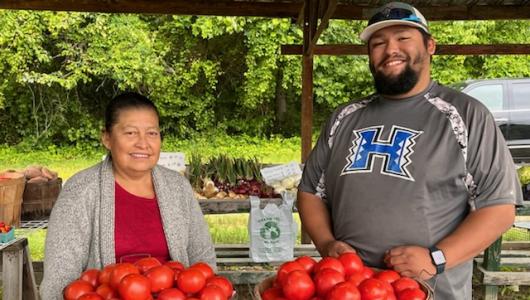 Two people standing in front of baskets of persimmons