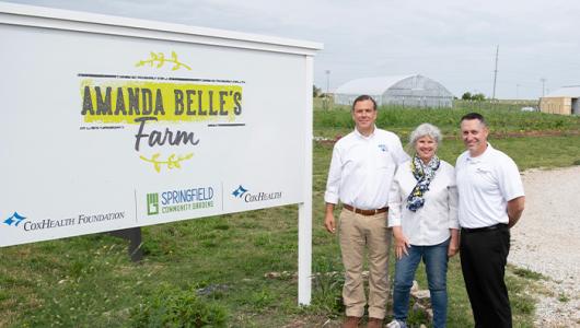 Three people standing in front of a sign