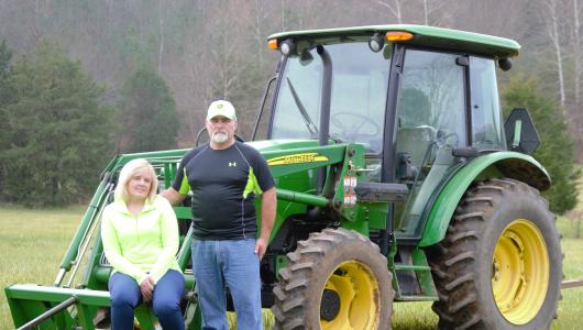 Two people sitting on a green tractor