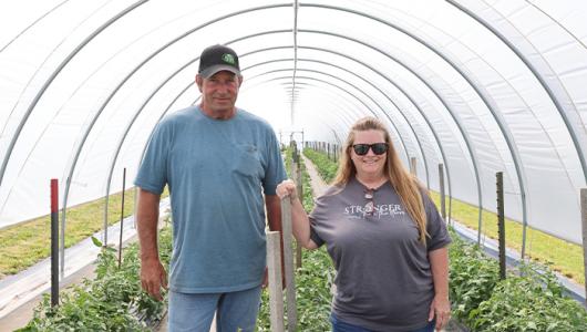 Two people standing in a high tunnel
