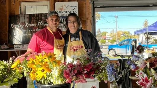 Two people standing behind a table of flowers